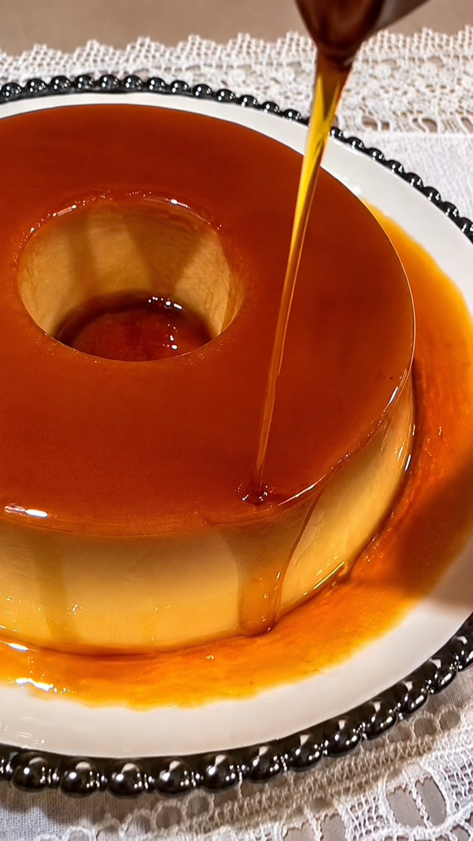 Calda de caramelo sendo derramada sobre um pudim tradicional da Pudim di Mãe